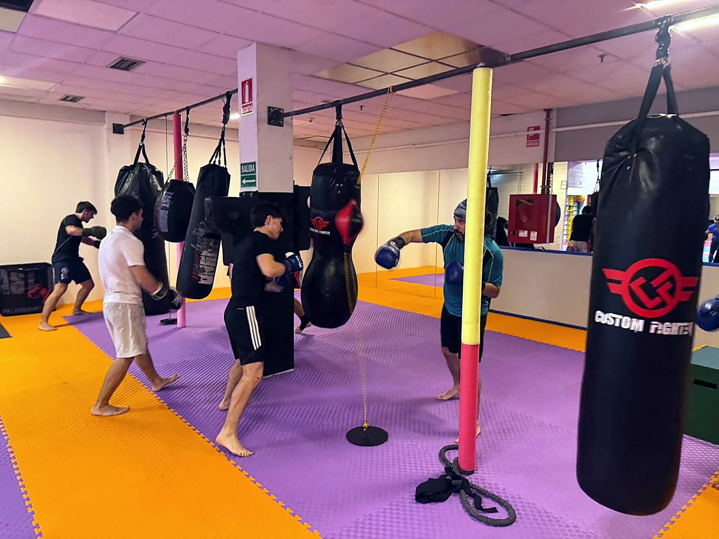 Alumnos adultos de ABP Sport entrenando con guantes en los sacos