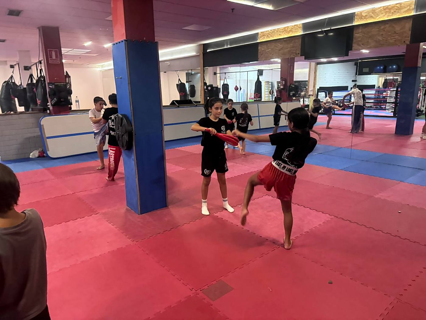 Dos niñas entrenando patadas con palas en la sala de ABP Sport