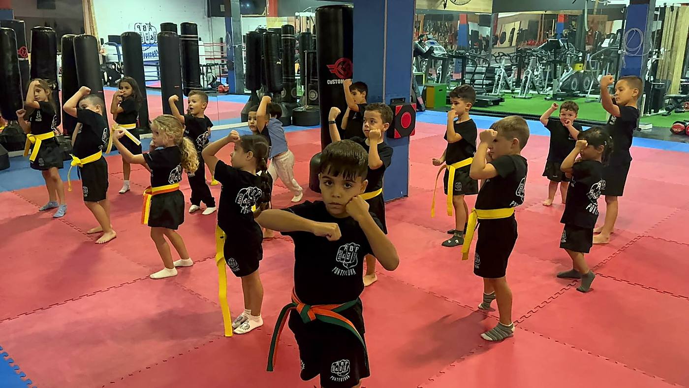 Niños y niñas en guardia con cinturones de colores en una clase infantil de ABP Sport