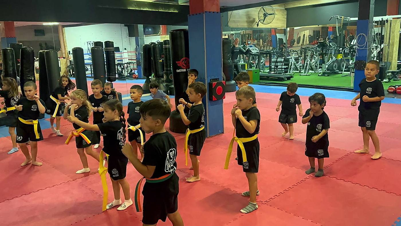 Niños y niñas con cinturón amarillo en posición de guardia en la sala de ABP Sport