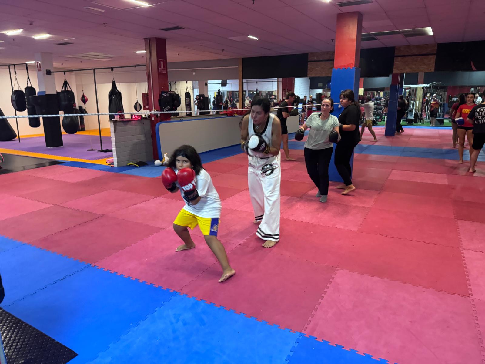 Clase de boxeo en la sala de ABP Sport: una niña y varias personas adultas en guardia con guantes