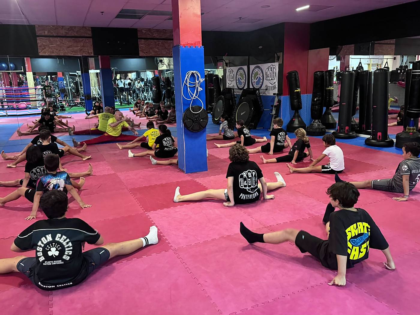 Clase infantil estirando en la sala de ABP Sport, con el profesor guiando al grupo